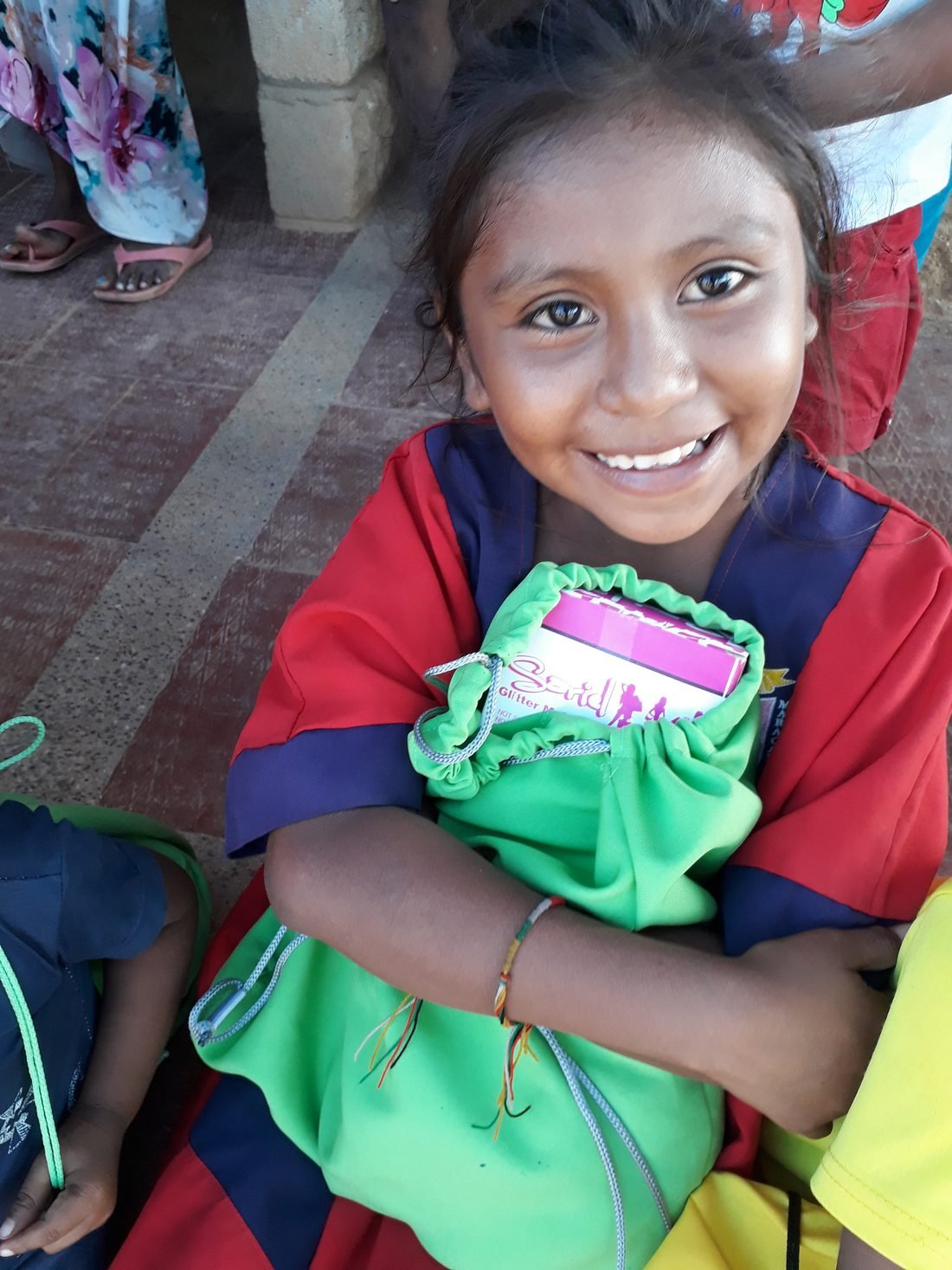 Niña wayúu sonríe mostrando el kit escolar que acaba de recibir