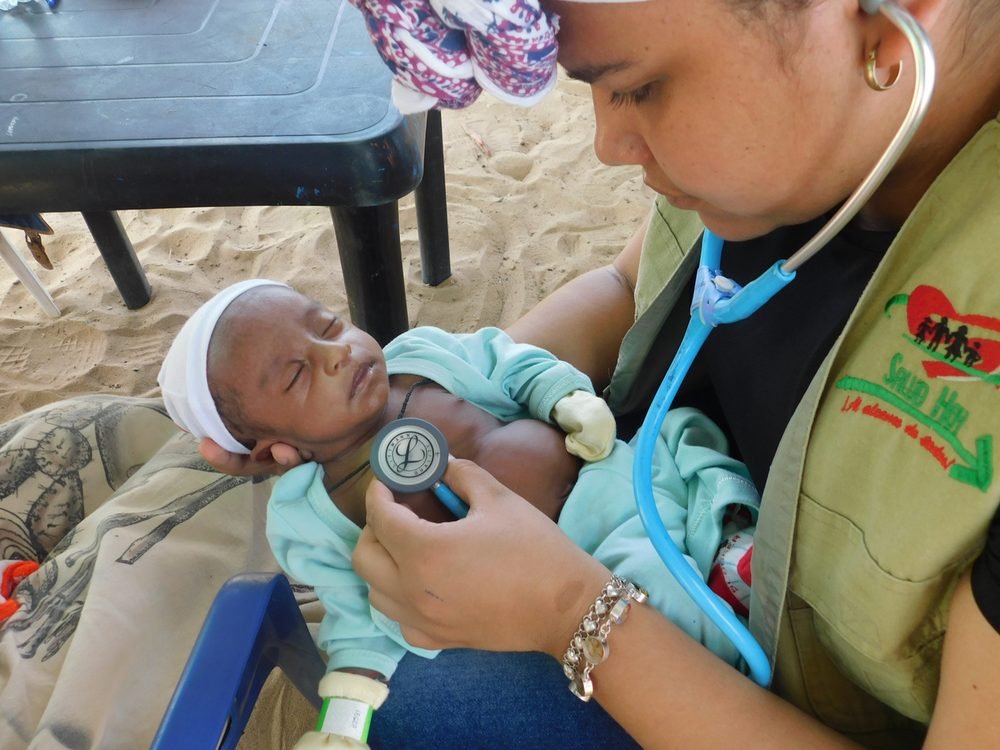 Enfermera valorando a un bebé con estetoscopio durante una brigada de salud